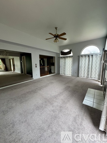 A spacious room with a ceiling fan and carpeted floor.