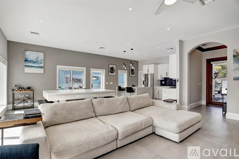A spacious living room with a large sectional sofa and a ceiling fan.