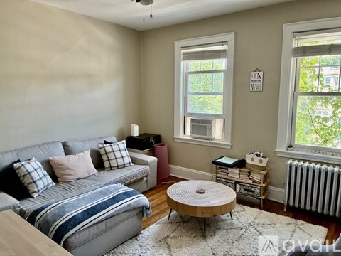 A living room with a grey couch and a round wooden table.