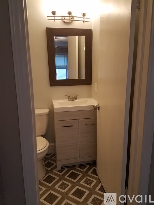A bathroom with a toilet, sink and mirror.