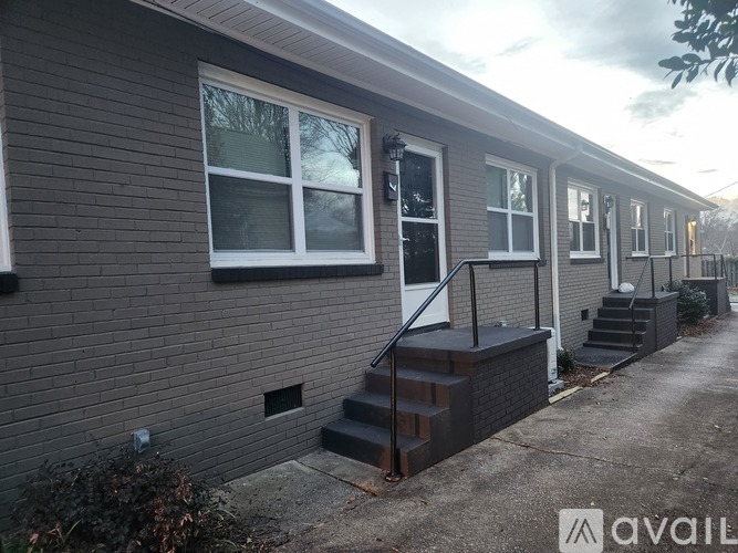 A house with a grey exterior and a white door is available for rent.