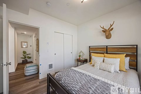 A bedroom with a bed, a deer head on the wall, and a striped ottoman.