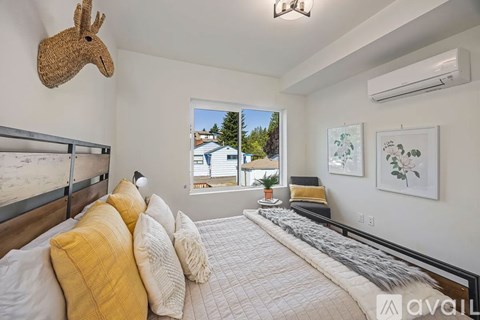 A bedroom with a bed, pillows, and a deer head on the wall.