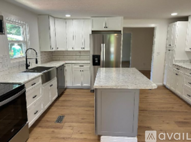 A kitchen with white cabinets and a marble island.