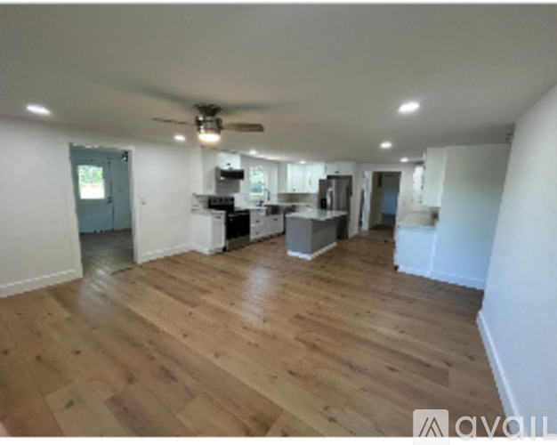 A spacious room with wooden flooring and a ceiling fan.