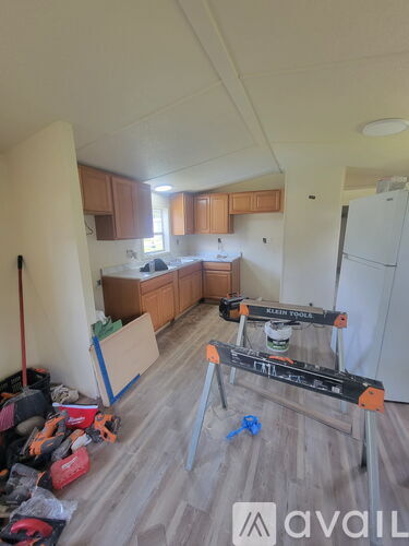 A room with a kitchen area and a white refrigerator.