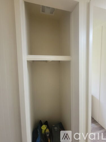 A white closet with a shelf and a few items on it.