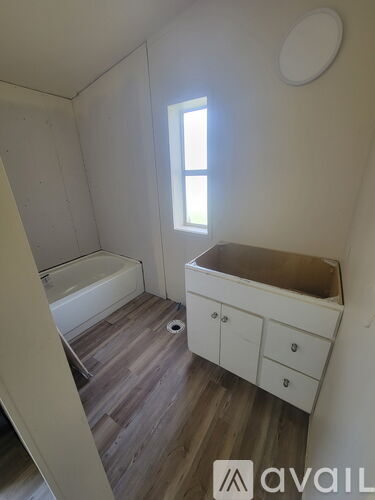 A bathroom with a tub, sink, and wooden floors.