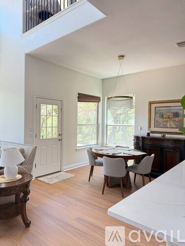 A dining room with a table set for two and a painting on the wall.