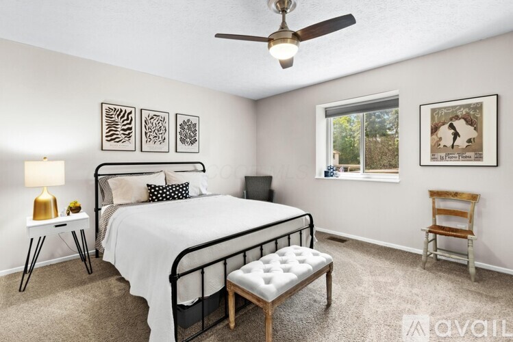 A bedroom with a bed, chair, and pictures on the wall.