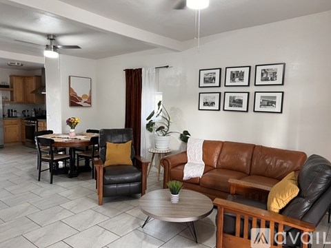 A living room with a brown leather couch and a dining table with chairs.