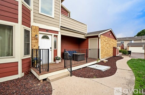 A red and beige house with a white door and a small garden area.
