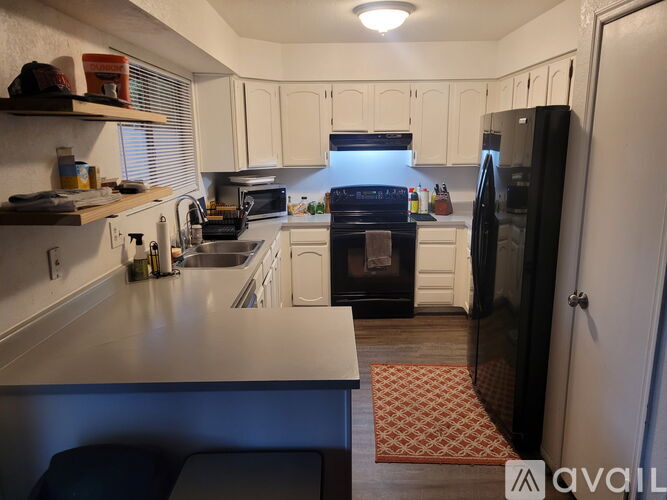 A kitchen with white cabinets and a black refrigerator.