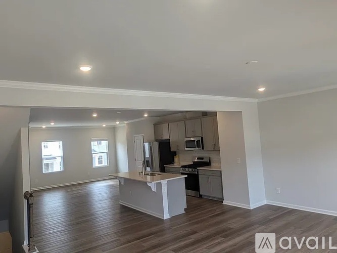 A spacious kitchen with white cabinets and a wooden floor.