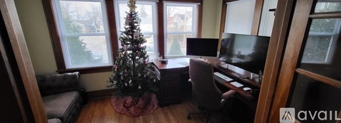 A Christmas tree is in a living room with a couch and a television.