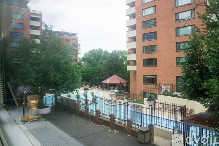 A pool area with a red umbrella and a fence.
