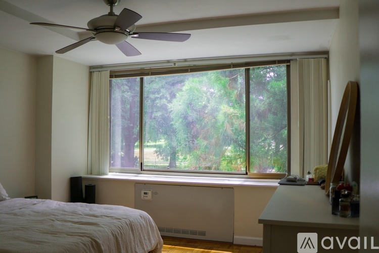 A bedroom with a bed, a window with a view of trees, and a ceiling fan.