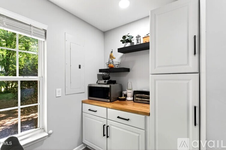 A kitchen with white cabinets and a window.
