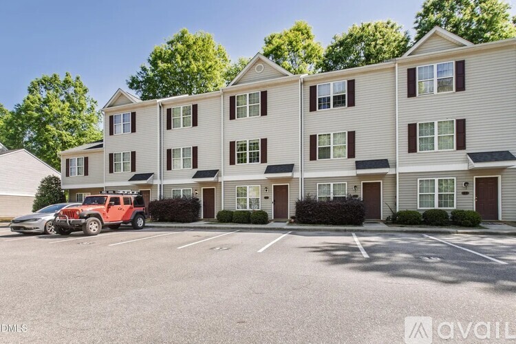 A red car is parked in front of a building with a sign that says "avail".