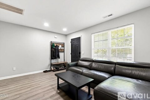 A living room with a black leather couch and a black TV.