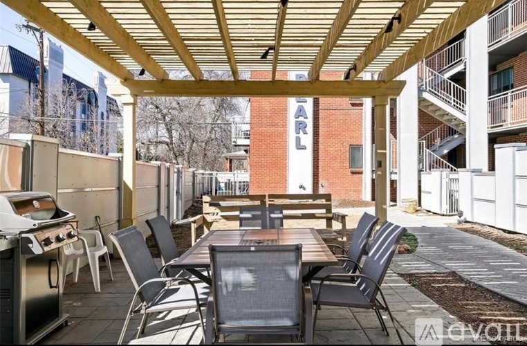 A patio with a table and chairs is covered by a wooden roof.