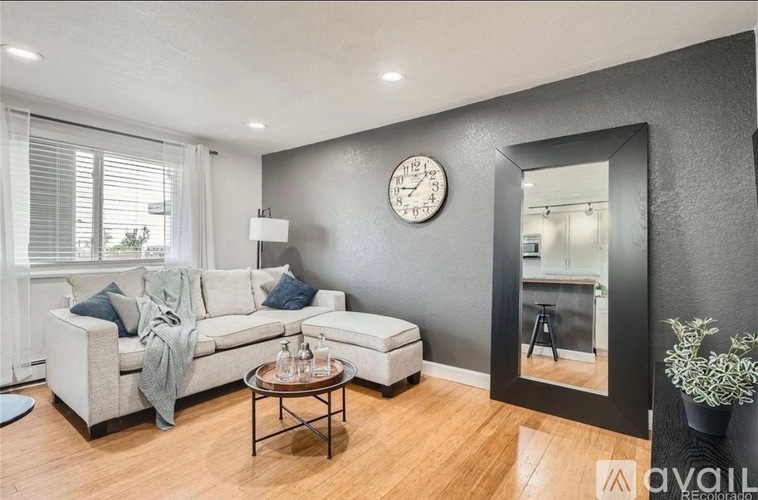 A living room with a grey couch, a coffee table, and a large mirror.