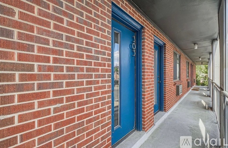 A red brick wall with a blue door and a white door handle.