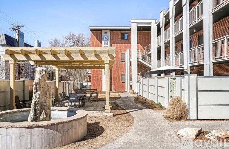 A patio with a table and chairs is surrounded by a white fence and a building with a red brick facade.