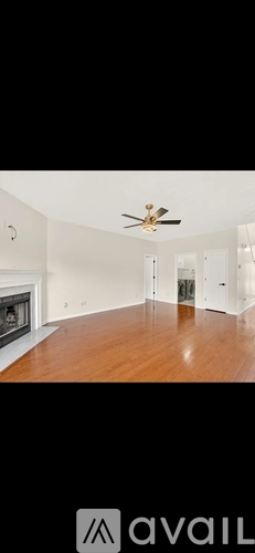 A spacious room with a fireplace and a ceiling fan.