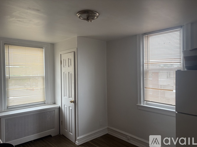 A room with a window covered in blinds, a door, and a radiator.