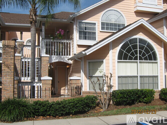 A house with a balcony and a tree in front.