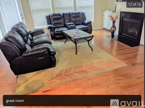 A living room with a black leather couch and a coffee table.