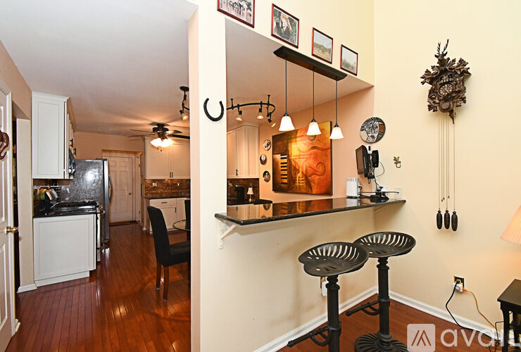 A kitchen with a refrigerator, stove, and bar stools.