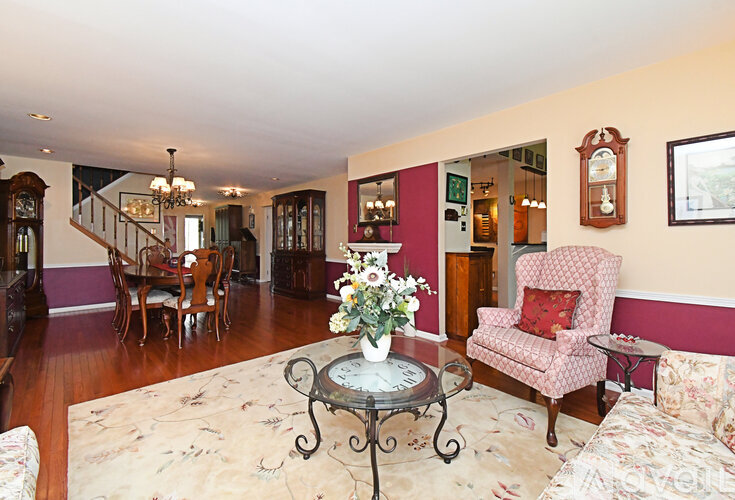 A living room with a pink chair and a table with a vase of flowers on it.