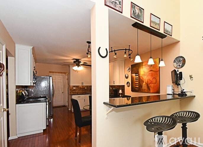 A kitchen with a black counter top and a black chair.