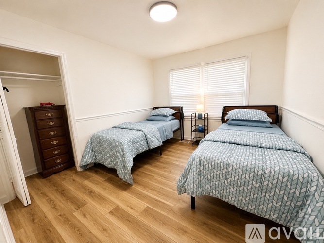 A bedroom with two beds and a wooden floor.