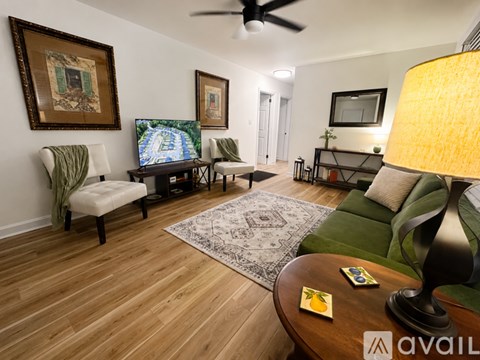 A living room with a TV, a couch, a chair, a coffee table, and a rug.