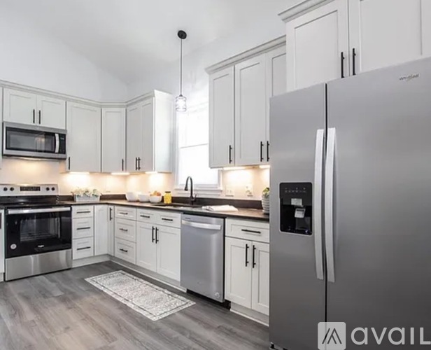 A modern kitchen with white cabinets and a stainless steel refrigerator.