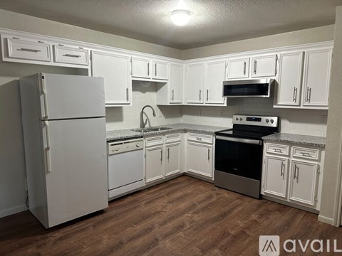 A kitchen with white cabinets and a refrigerator.