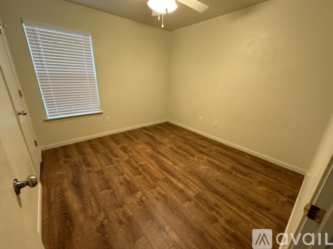 A room with wooden flooring and a window with blinds.