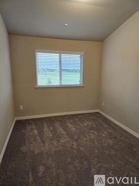 A room with a carpeted floor and a window with blinds.