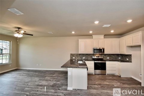 A spacious kitchen with a fan on the ceiling and a stove top oven.