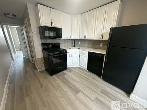 A kitchen with black appliances and white cabinets.