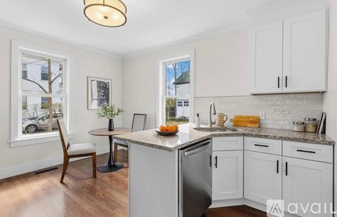 A kitchen with white cabinets and a marble countertop.