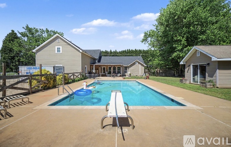A pool with a bench in front of a house with a sign that says "available".