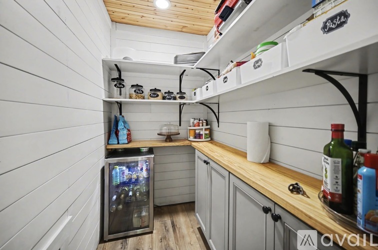 A kitchen with a refrigerator and wooden shelves.