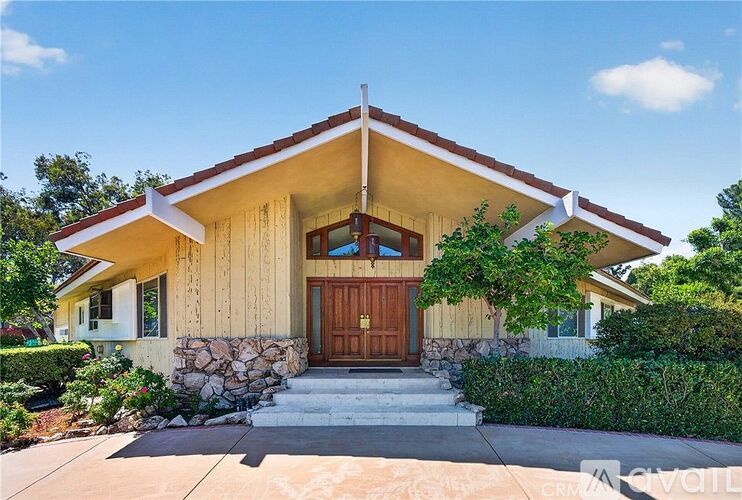 A house with a stone wall and a brown door.