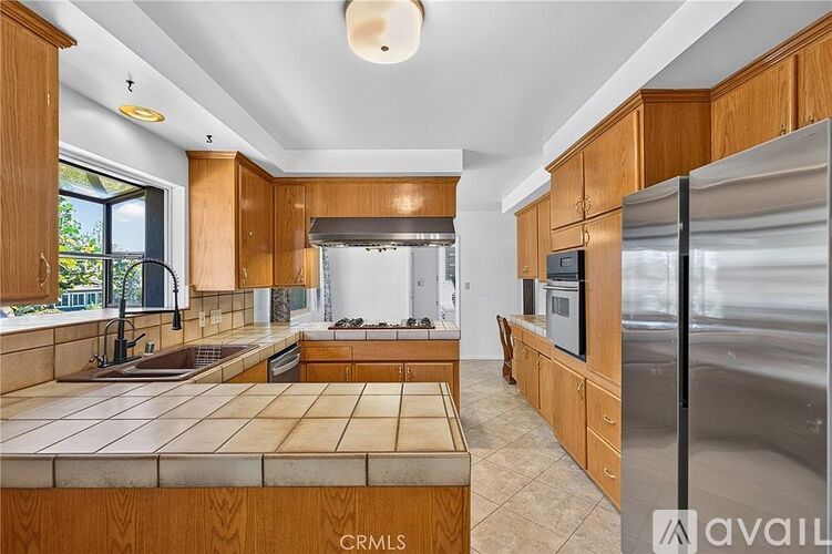 A kitchen with wooden cabinets and a stainless steel refrigerator.