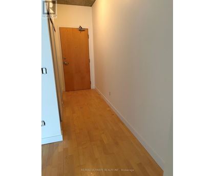 A hallway with a wooden door and floor.