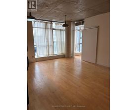 A room with wooden floors and a large window with curtains.